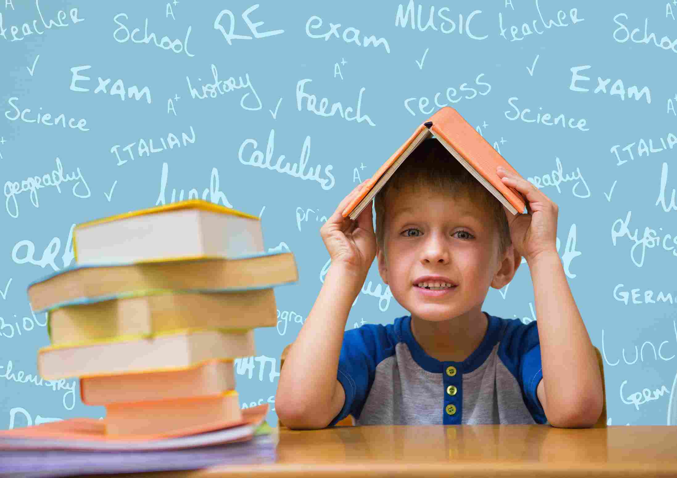 A young boy with a book on his head, sitting at a desk with school books, representing the stress of 11 Plus Maths Exams.