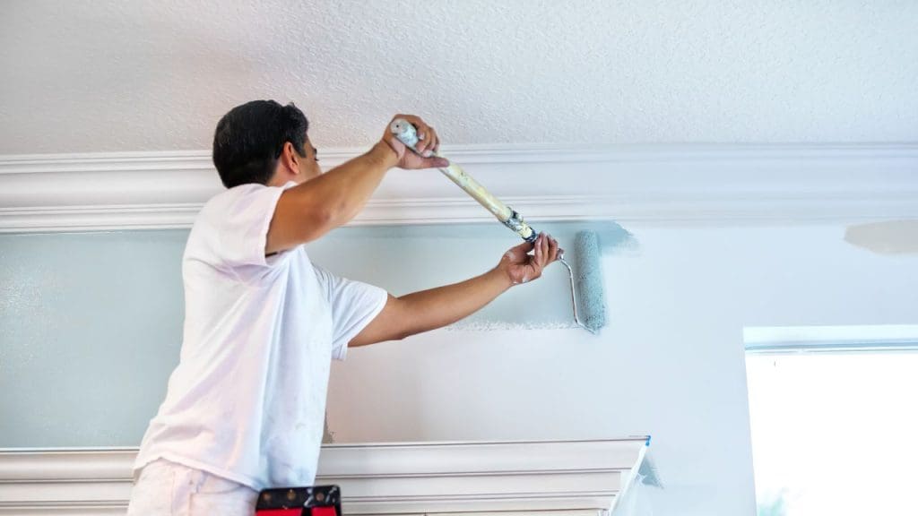Skilled-painter-applying-fresh-white-paint-to-a-living-room-wall-using-a-roller