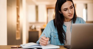A woman is writing down notes on SEO content writing and how to write clear and engaging blogs for her business website.