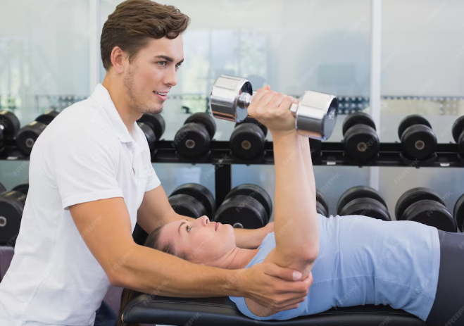 Trainer guiding woman doing dumbbell chest press on bench in gym